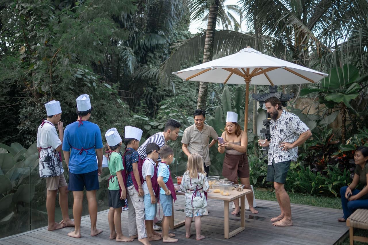Kids in chef hats making their own pizzas at a Bali villa party