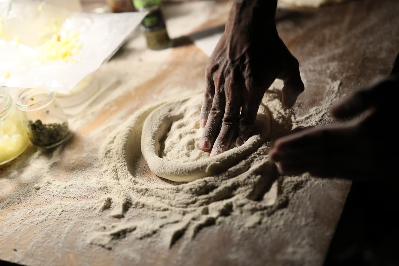 Hands stretching pizza dough on a floured board