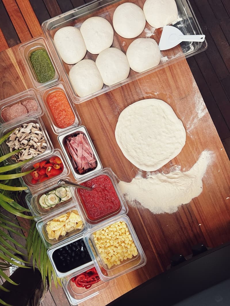 Fresh dough and a full spread of toppings, laid out and ready to build your pizza