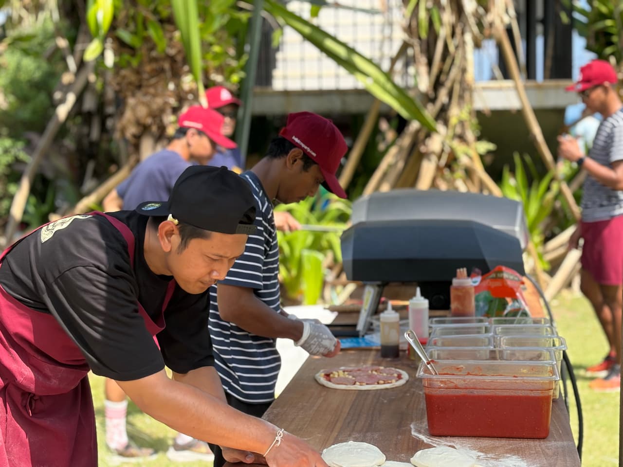 Our team hand-topping pizzas at the prep station before they go in the oven