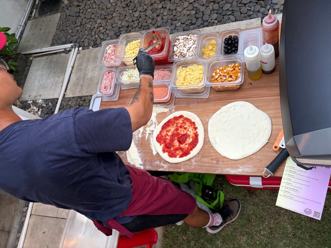 Saucing a pizza base next to the toppings at De La Vie Villa, Seminyak