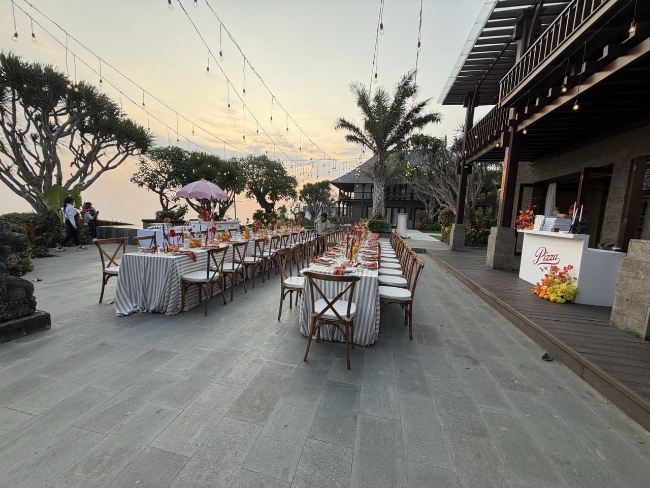 Long dinner tables under string lights on the terrace at Stone Villas at sunset